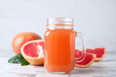 Photo of Tasty freshly made grapefruit juice on white marble table