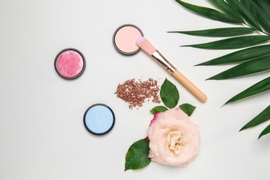 Photo of Flat lay composition with makeup brush, cosmetic products  and rose on white background