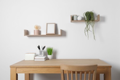 Photo of Comfortable workplace with wooden desk near white wall at home