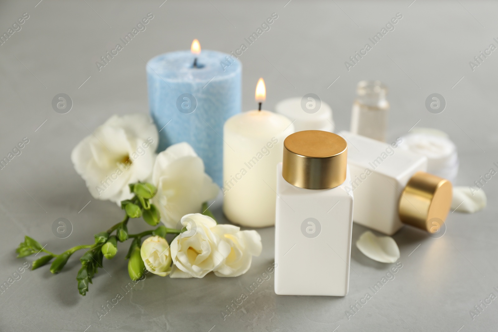 Photo of Beautiful spa composition with cosmetic products, flowers and candles on light grey table