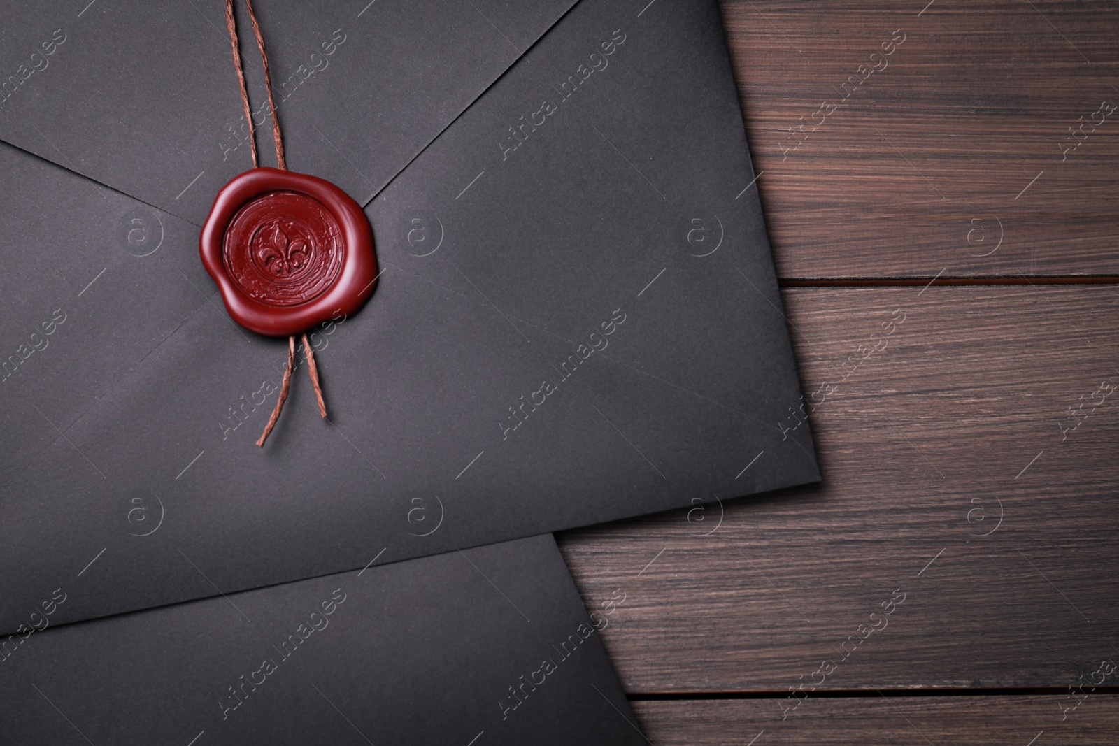 Photo of Black envelopes with wax seal on wooden background, flat lay