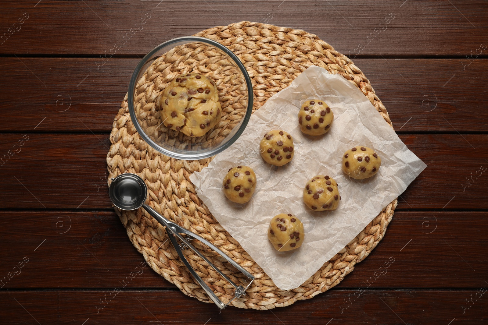 Photo of Fresh dough and uncooked chocolate chip cookies on wooden table, top view