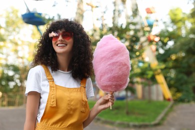 Photo of Portrait of happy woman with cotton candy at funfair. Space for text