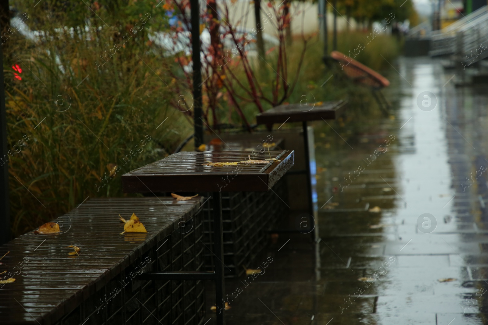 Photo of Wet tables and benches on city street after rain