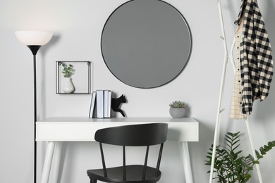 Photo of Stylish room interior with round mirror on white wall over desk