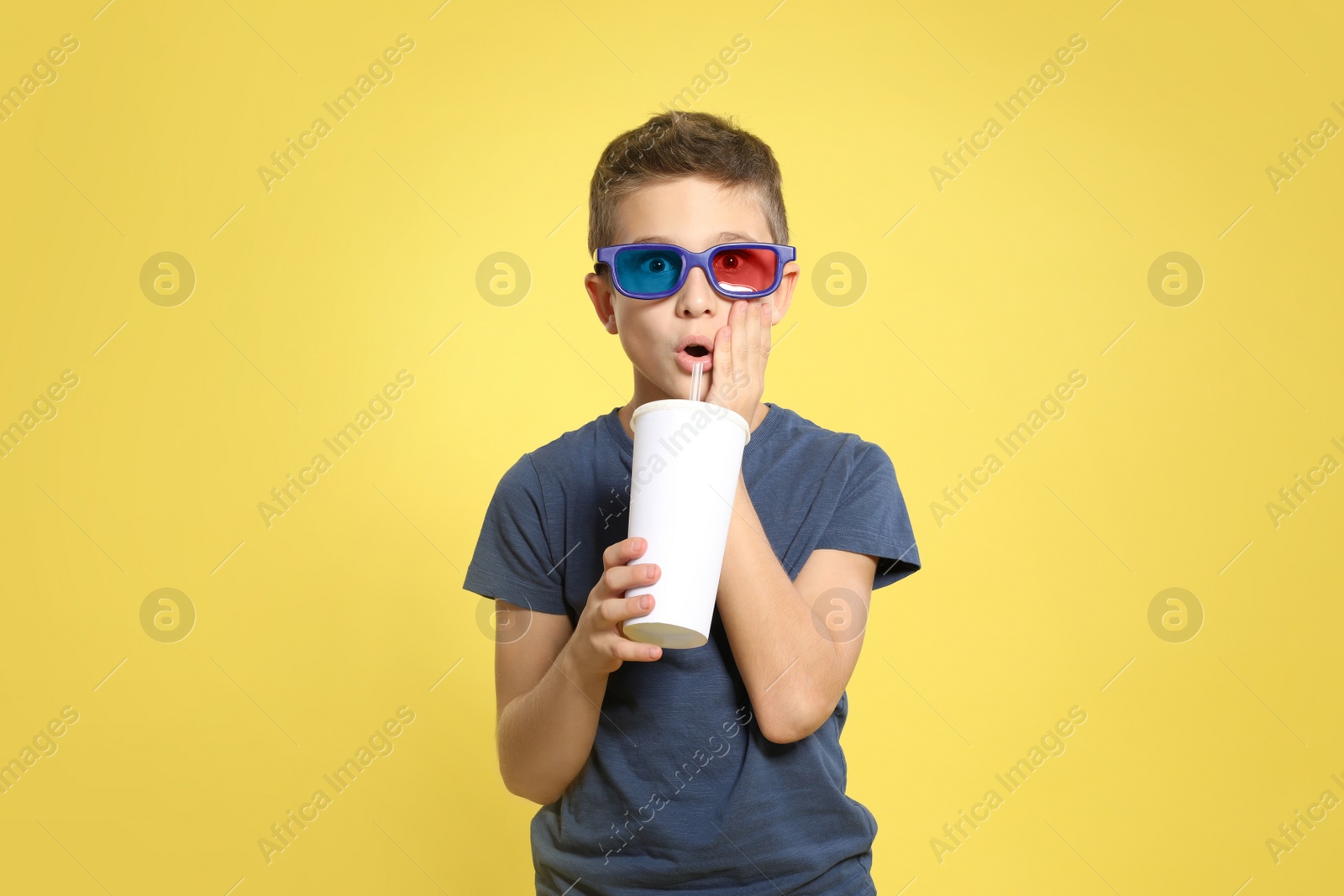 Photo of Boy with 3D glasses and beverage during cinema show on color background