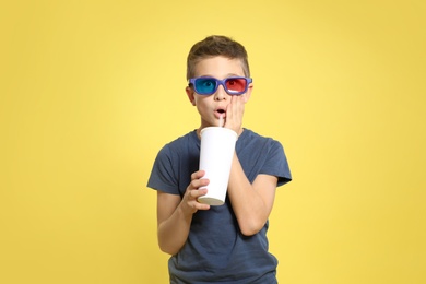 Photo of Boy with 3D glasses and beverage during cinema show on color background