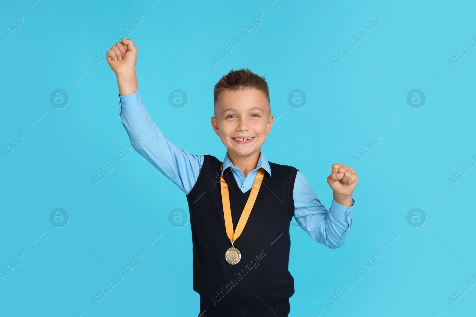 Photo of Happy boy in school uniform with golden medal on blue background