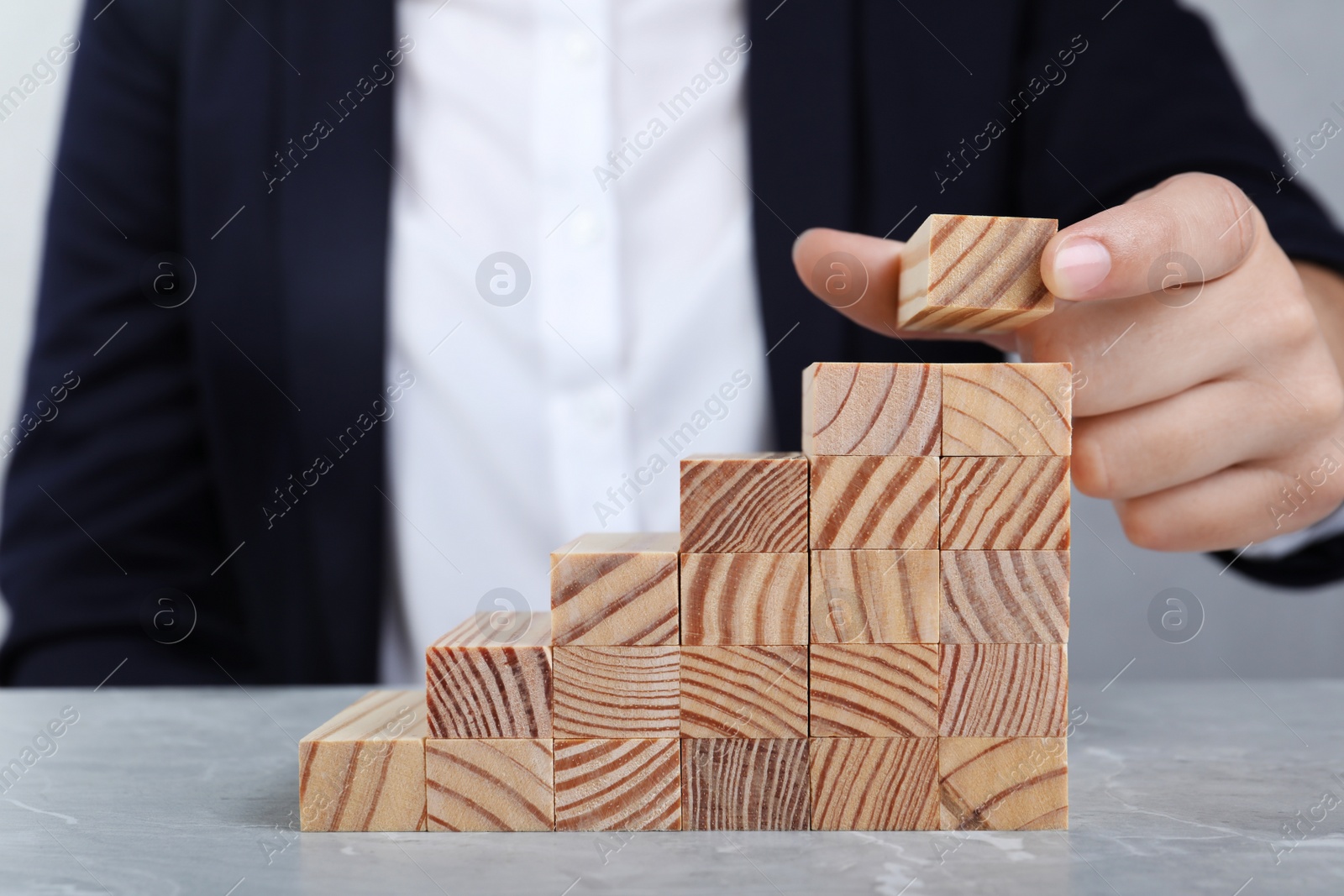 Photo of Businesswoman building steps with wooden blocks at table, closeup. Career ladder