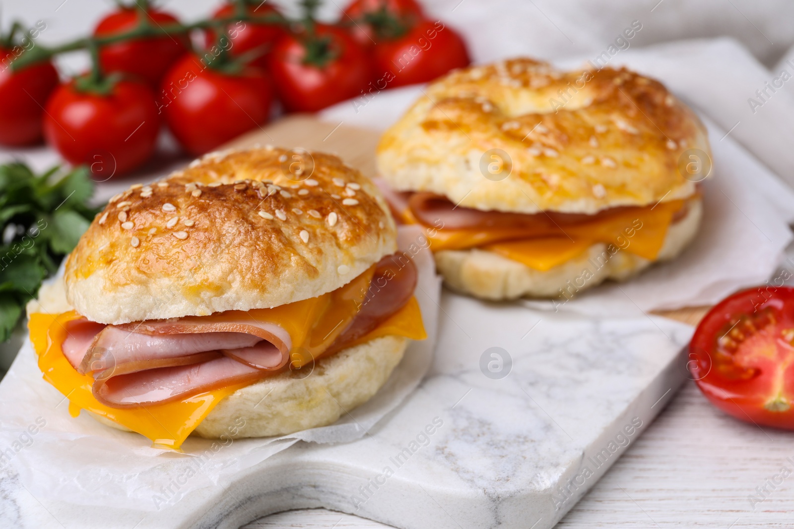 Delicious bagels with ham and cheese on white table, closeup. Space for text Photo of Delicious bagels with ham and cheese on white table, closeup. Space for text