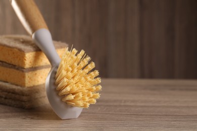 Photo of Cleaning brush and sponges on wooden table, space for text