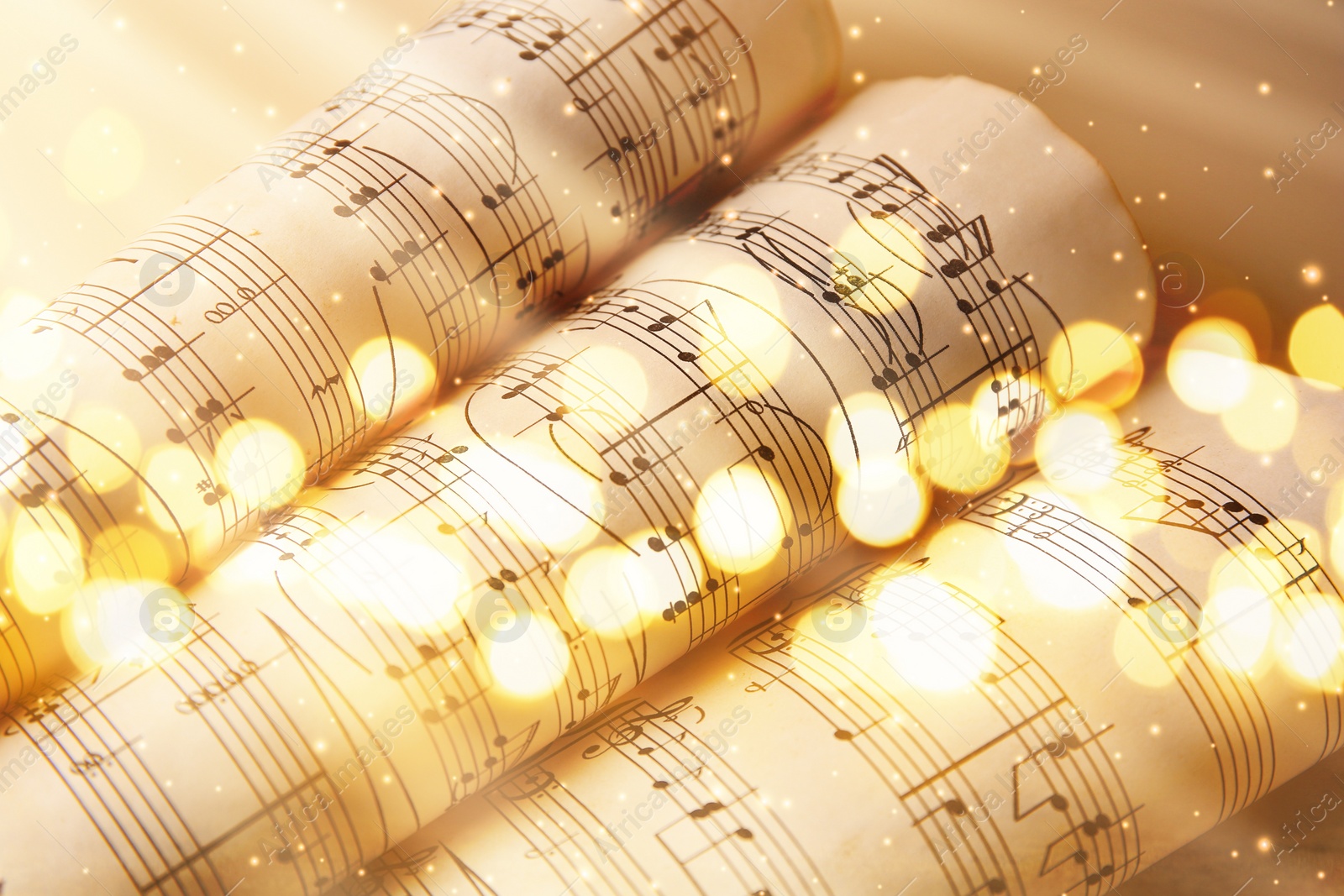 Image of Rolled sheets with music notes on gold background, bokeh effect