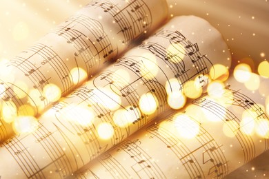 Rolled sheets with music notes on gold background, bokeh effect