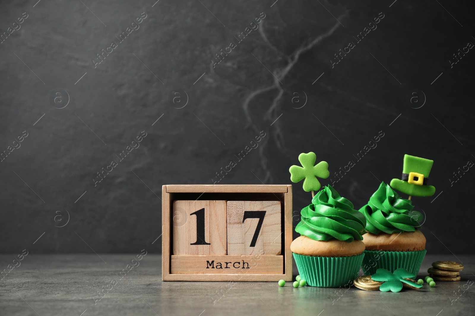 Photo of Decorated cupcakes, wooden block calendar and coins on table. St. Patrick's day celebration