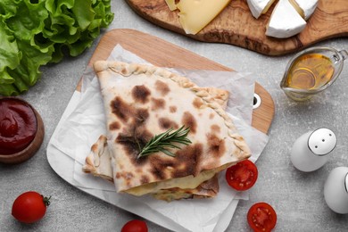 Photo of Tasty pizza calzones with cheese and different products on light grey table, flat lay