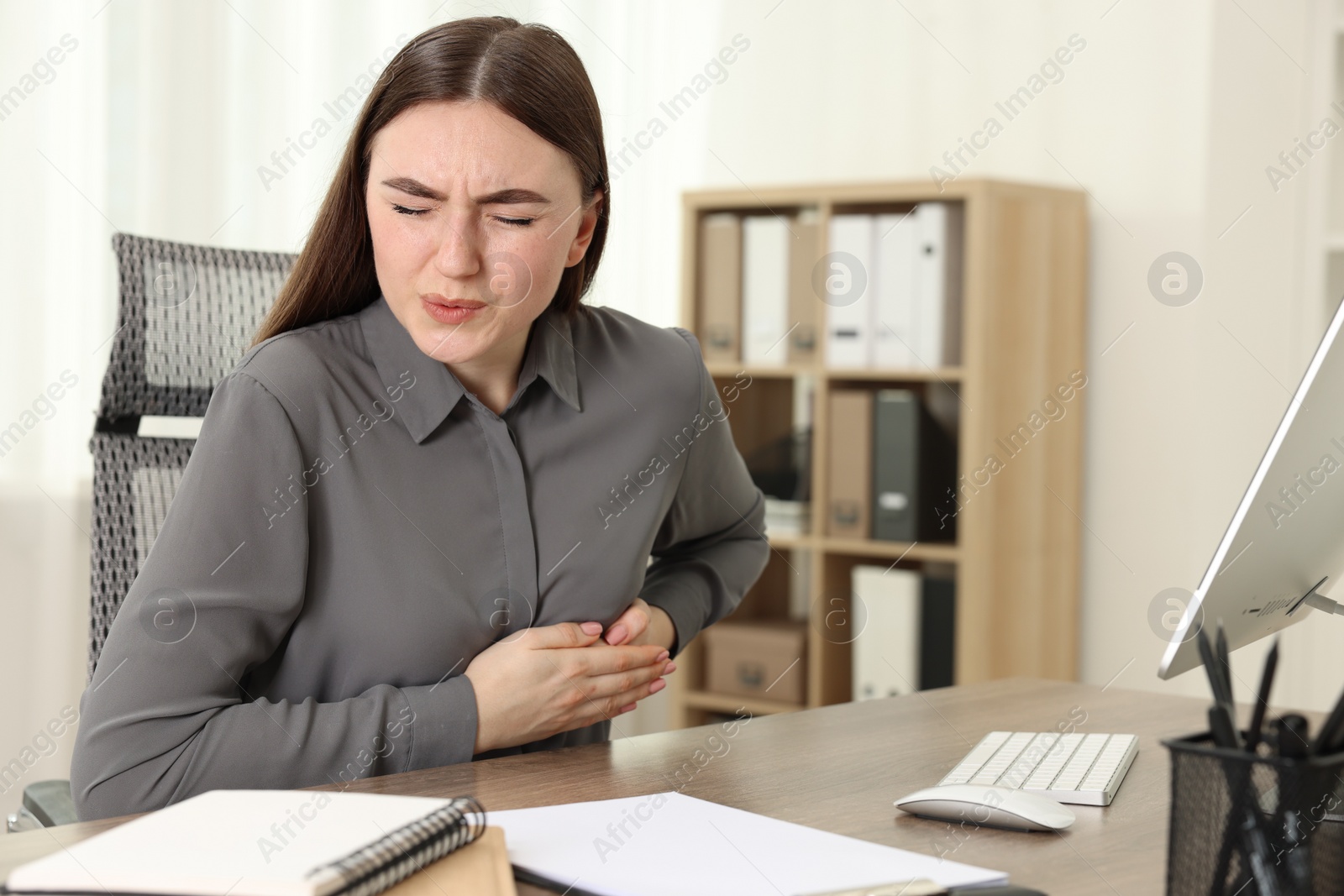 Photo of Woman having heart attack at table in office