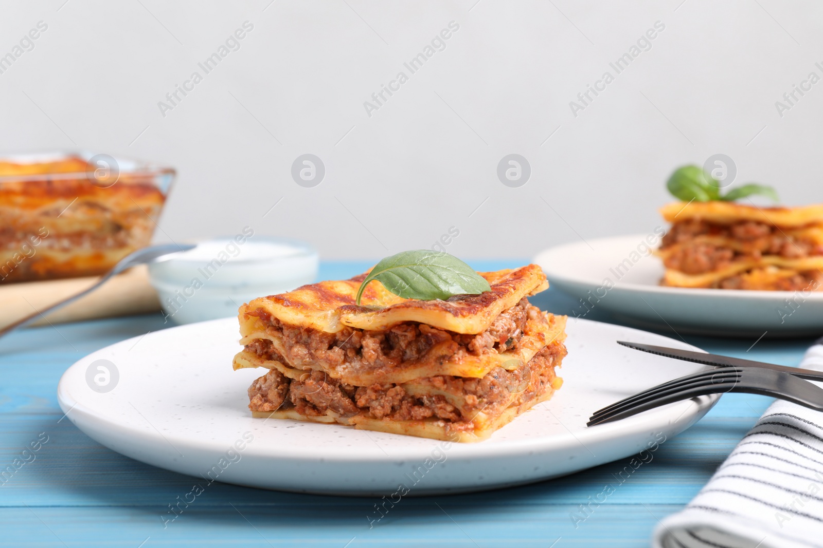 Photo of Tasty cooked lasagna served on light blue table