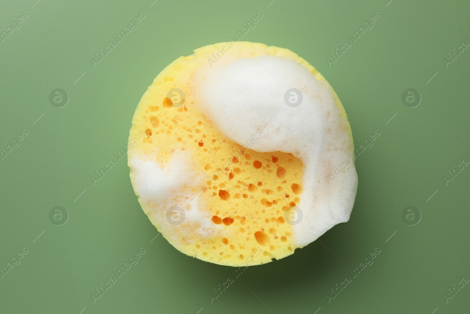 Photo of Yellow sponge with foam on green background, top view