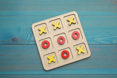 Tic tac toe set on light blue wooden table, top view