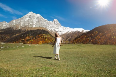 Young woman walking in beautiful mountains on sunny day