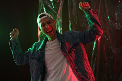 Photo of Happy young man on dark background in neon lights