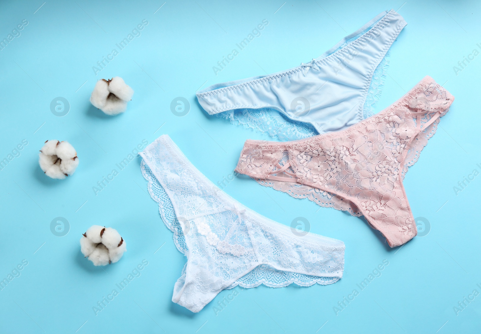 Photo of Women's underwear and cotton flowers on light blue background, flat lay