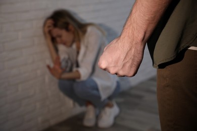 Man threatening scared woman indoors, closeup. Domestic violence