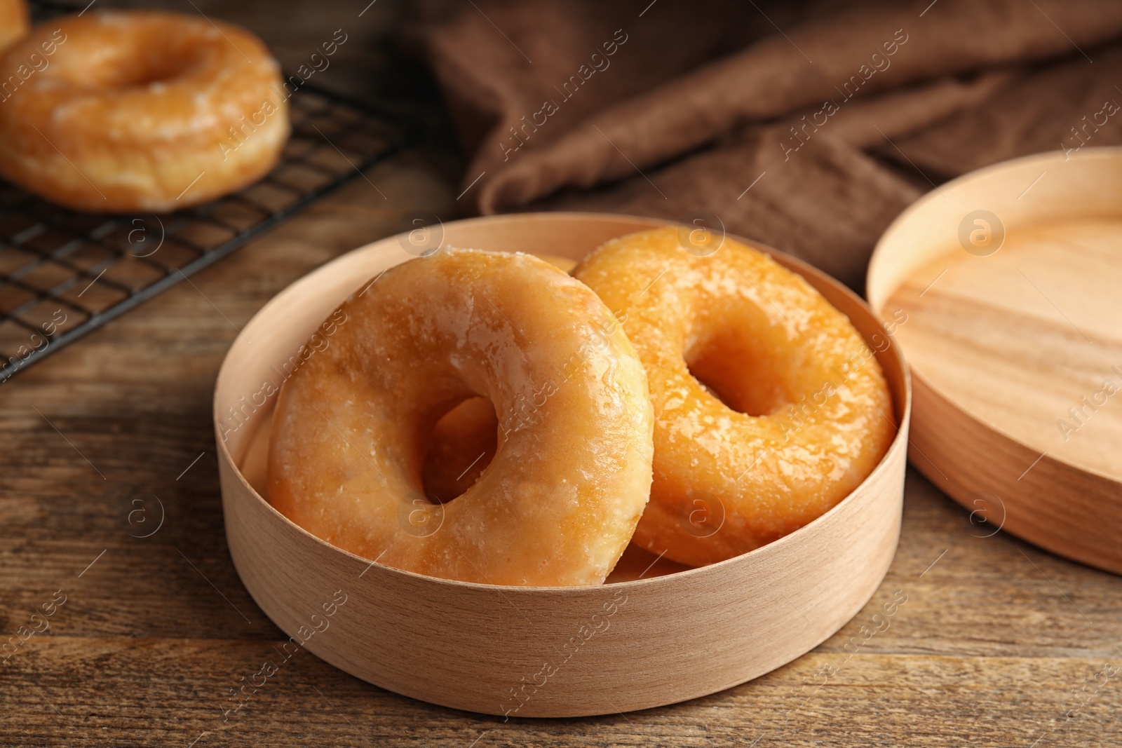 Photo of Delicious donuts in box on wooden table