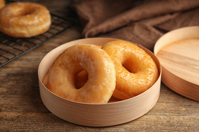 Delicious donuts in box on wooden table