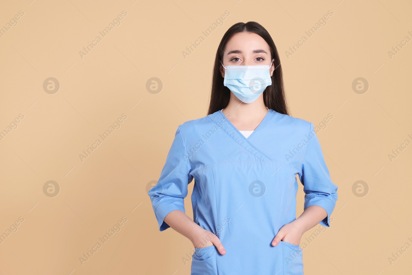 Photo of Nurse wearing protective mask on light brown background, space for text