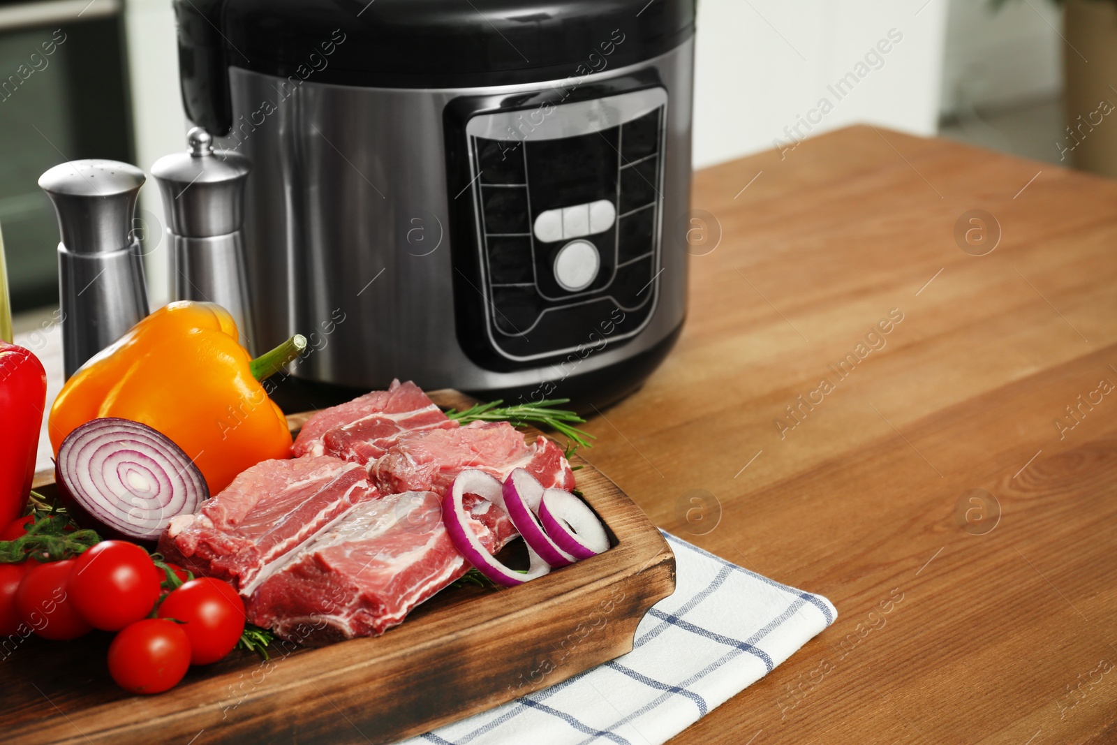 Photo of fresh ingredients and modern multi cooker on wooden table. Space for text