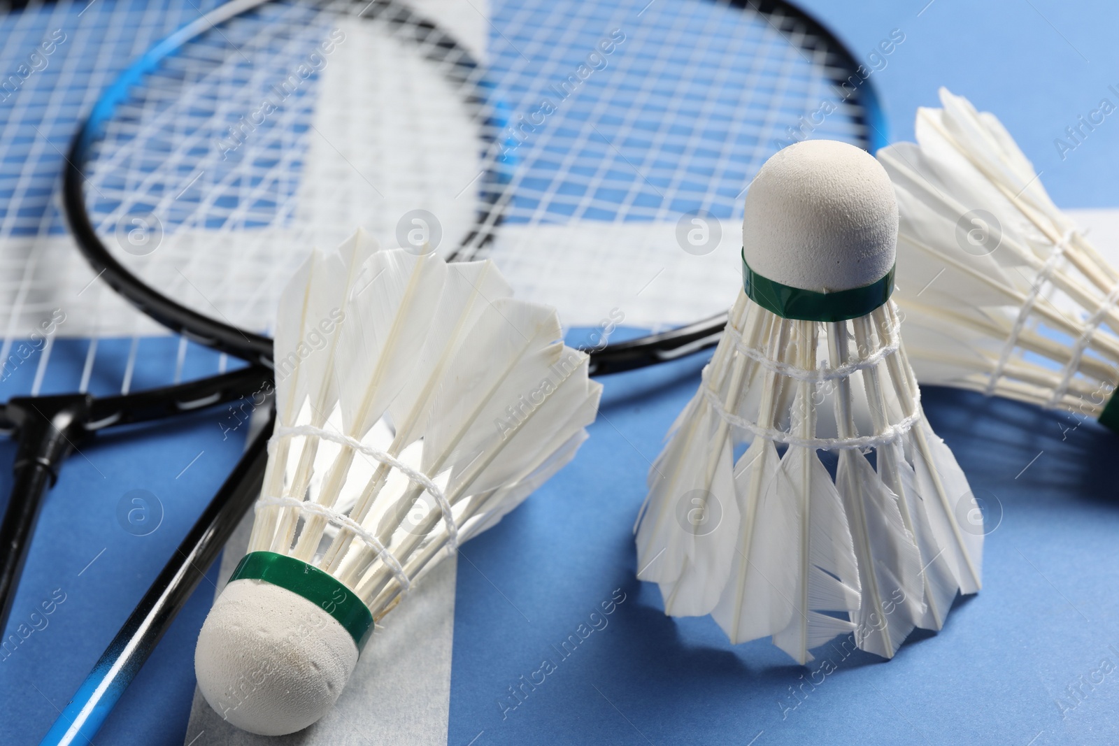 Photo of Feather badminton shuttlecocks and rackets on blue background, closeup