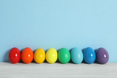 Easter eggs on white wooden table against light blue background, space for text