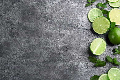 Photo of Lemonade layout with juicy lime slices and mint on grey table, top view. Space for text