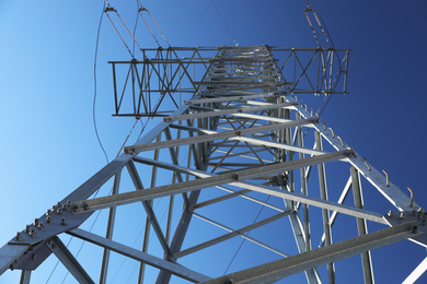 Photo of Modern high voltage tower against blue sky, low angle view