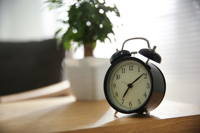 Alarm clock on wooden table at home. Morning time