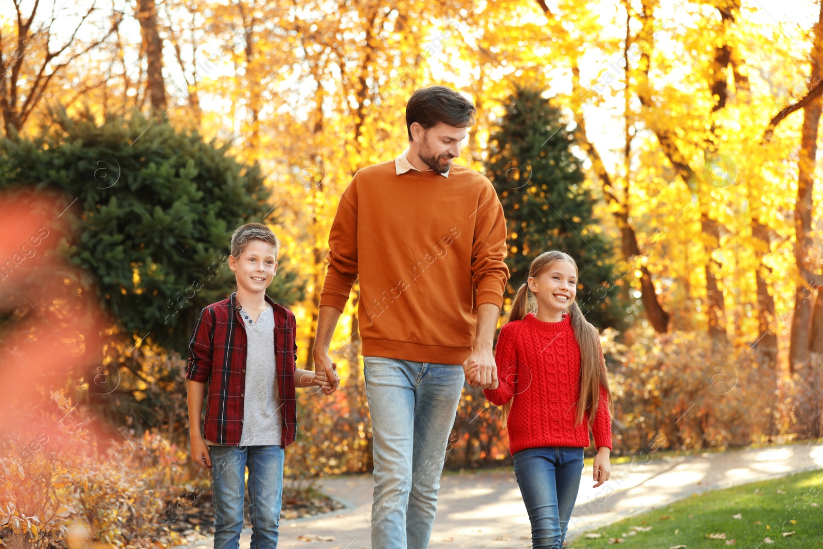 Photo of Happy father with children walking in autumn park