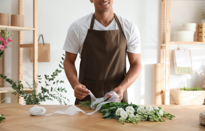 Photo of Florist making beautiful bouquet at table in workshop, closeup