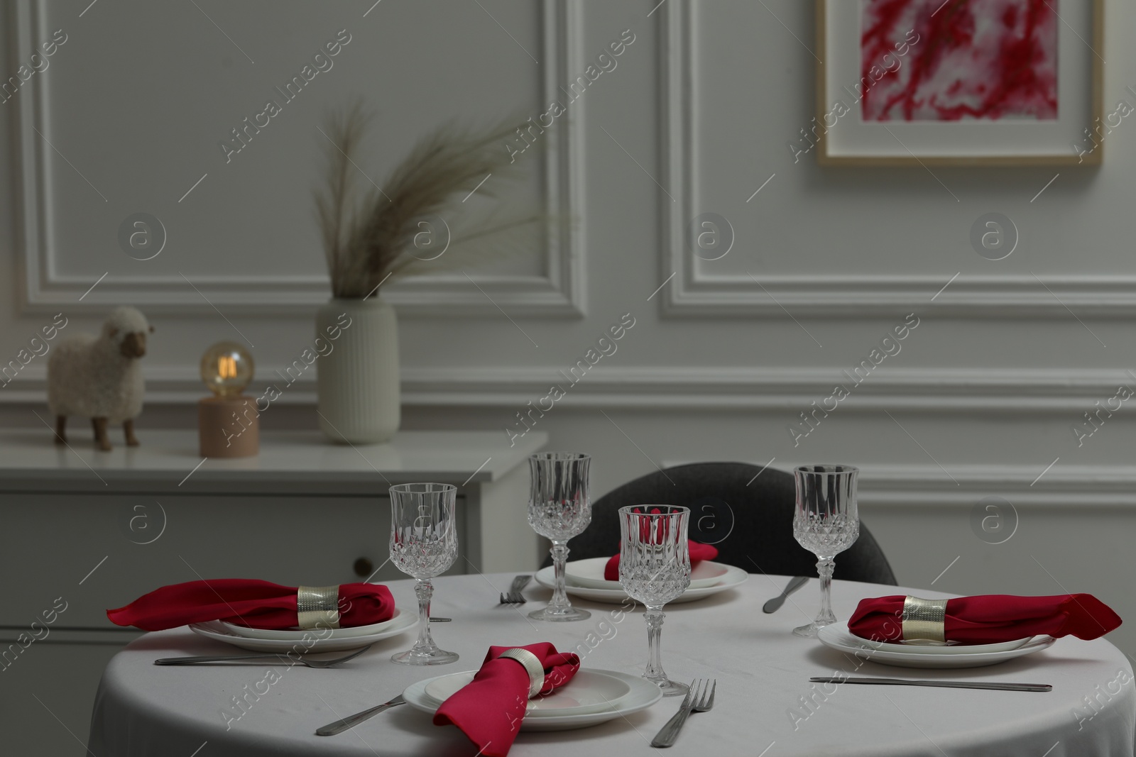 Photo of Color accent table setting. Glasses, plates, cutlery and pink napkins on table indoors