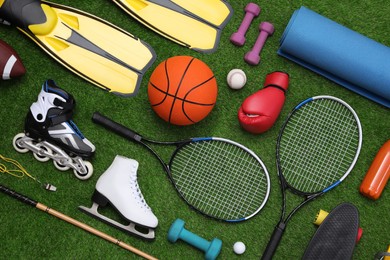 Different sport equipment on green grass, flat lay