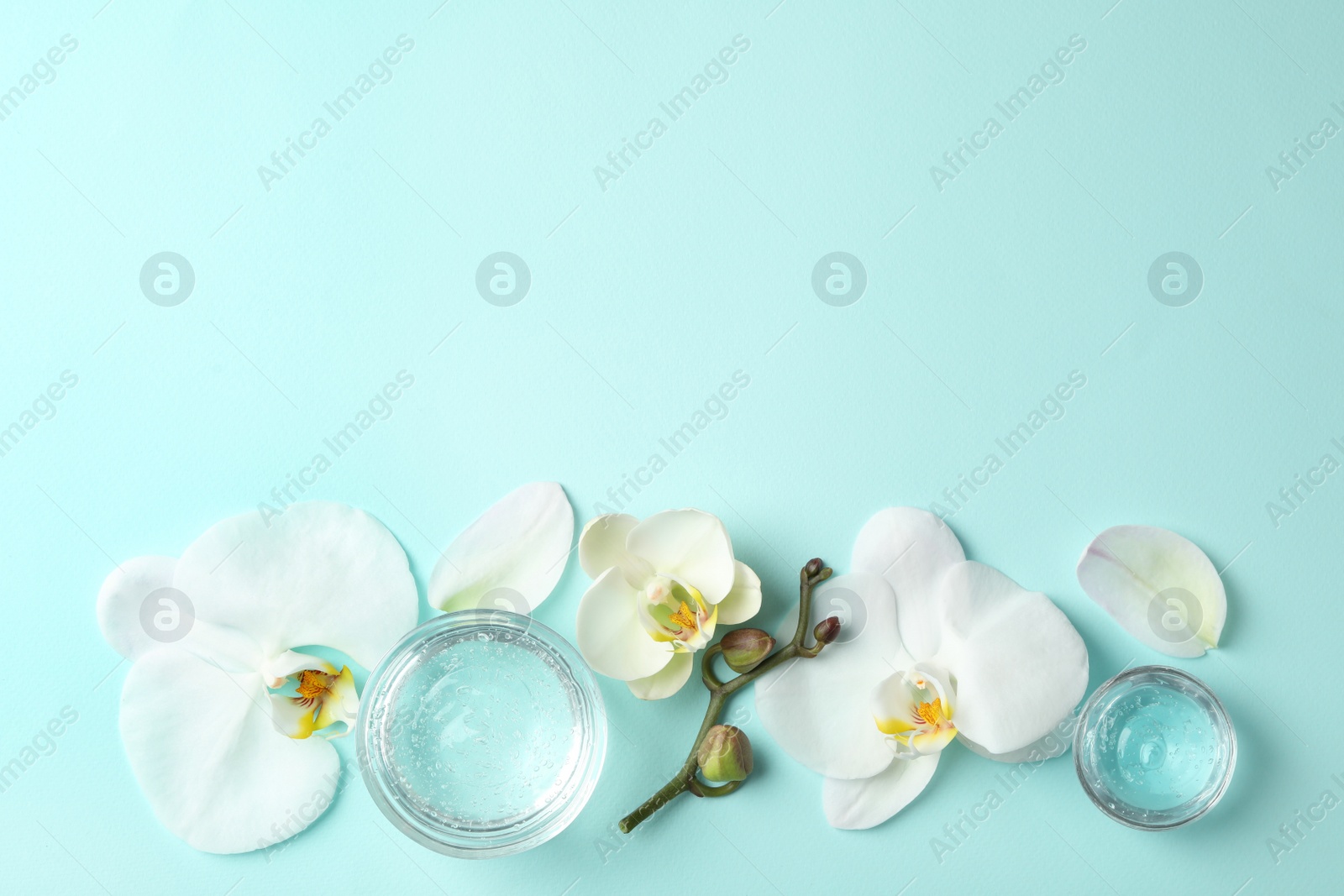 Photo of Flat lay composition with cosmetic gel and beautiful flowers on light blue background. Space for text