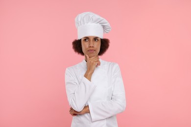 Photo of Portrait of thoughtful female chef in uniform on pink background