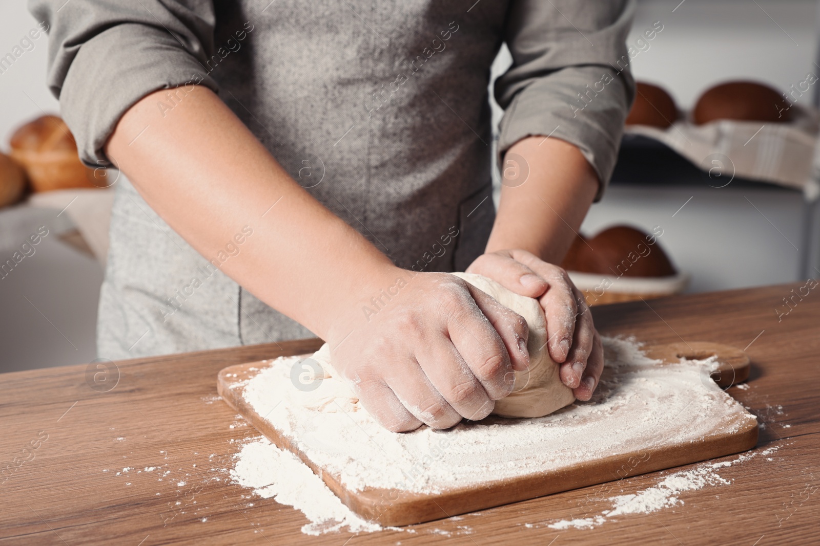 Photo of Man kneading dough at table in kitchen, closeup