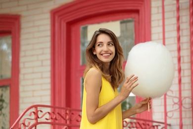 Photo of Happy young woman with cotton candy outdoors