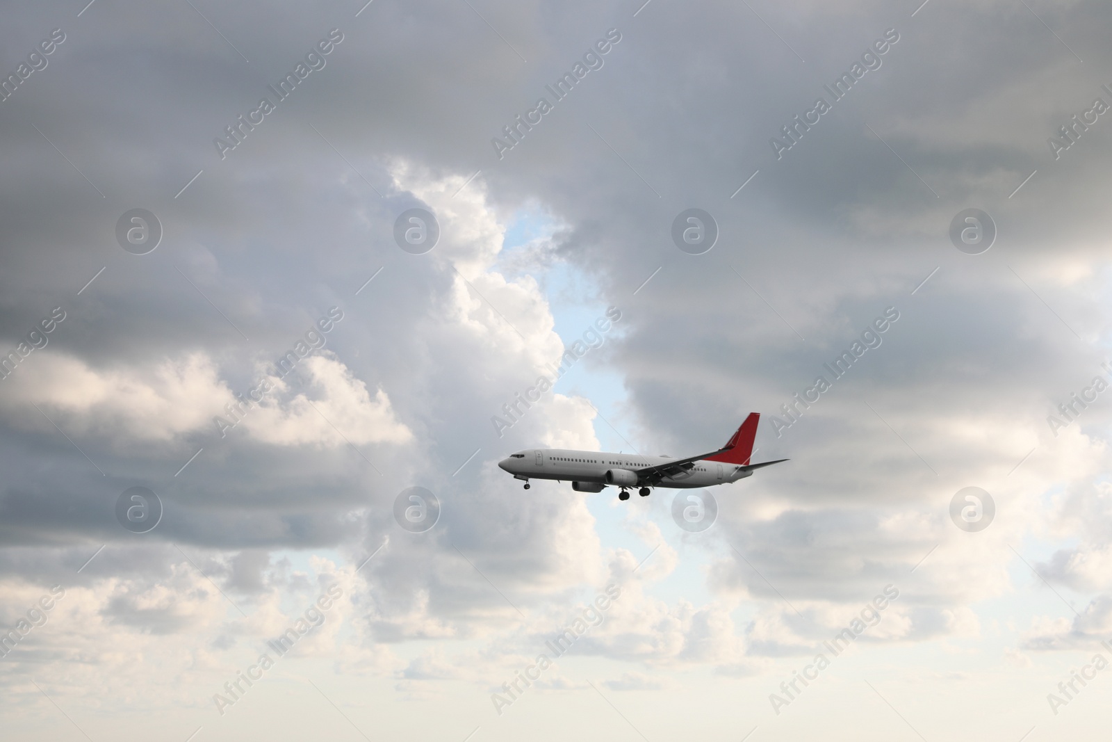 Photo of Modern white airplane flying in sky with clouds