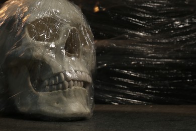 Photo of Human skull with stretch film on stone surface against black background, closeup. Space for text
