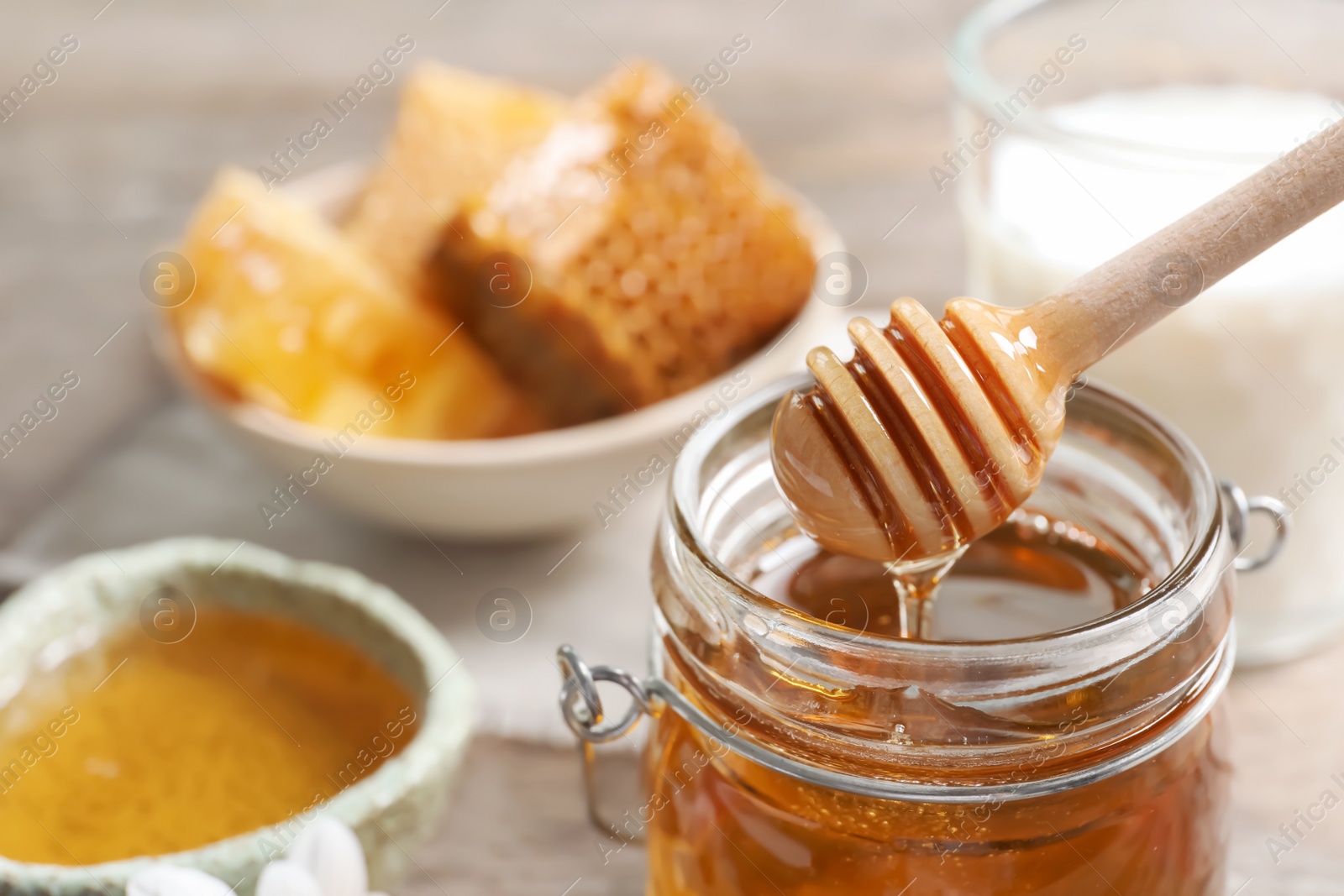 Photo of Honey pouring from dipper into jar, closeup