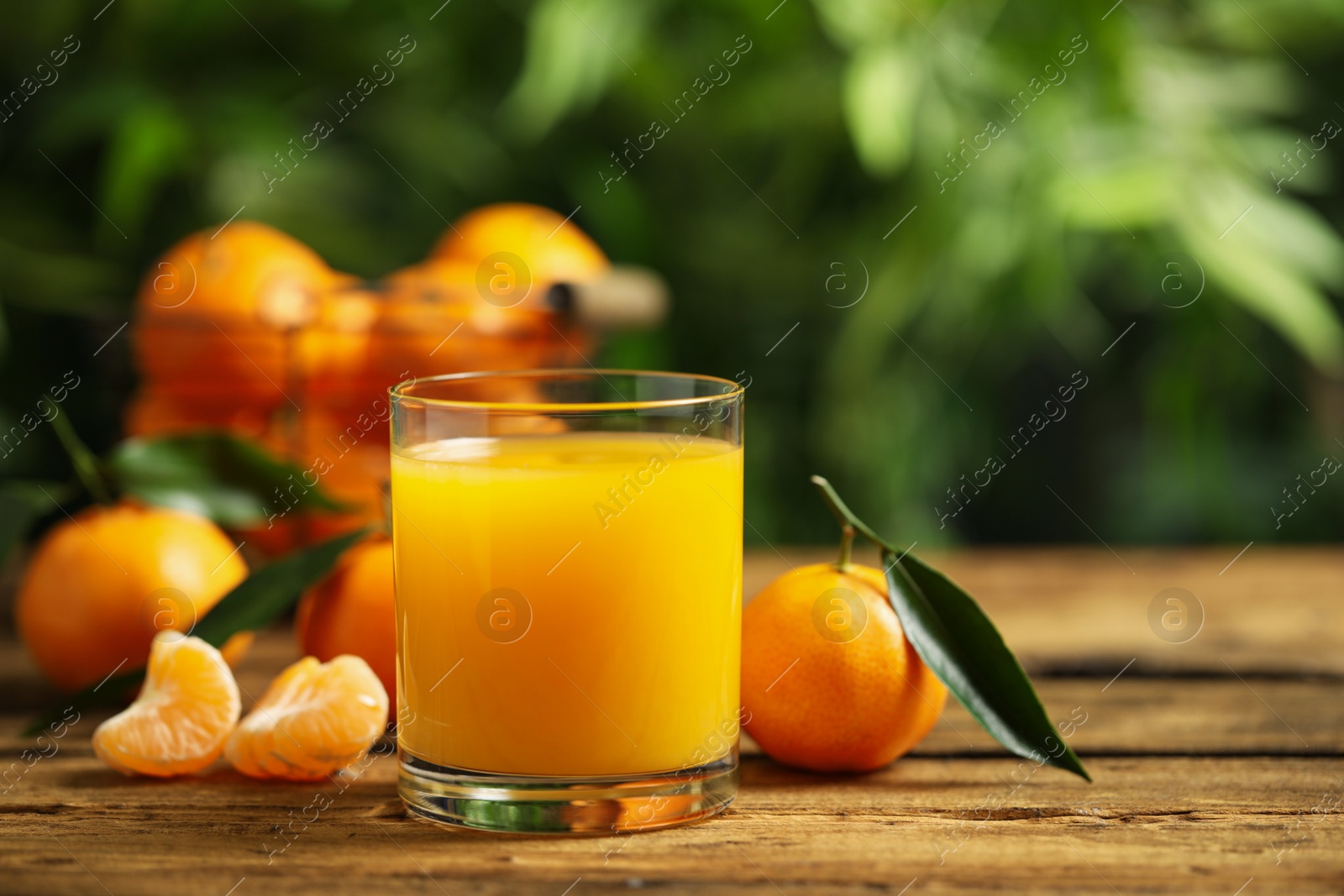 Photo of Glass of fresh tangerine juice and fruits on wooden table