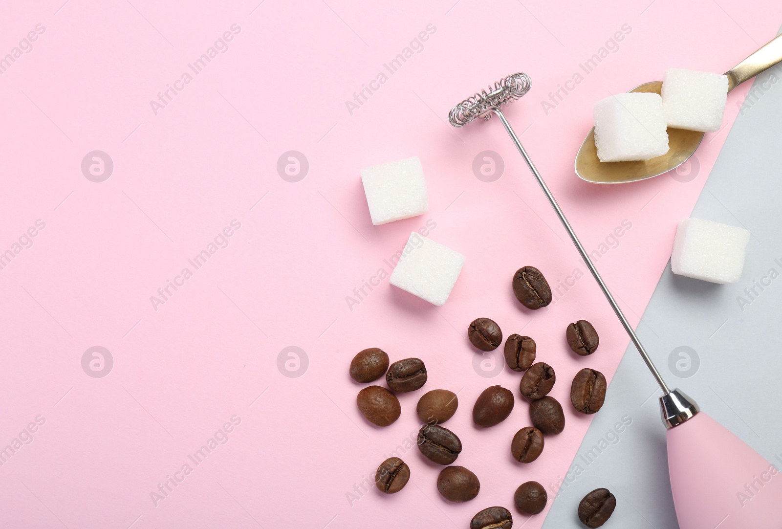 Photo of Pink milk frother wand, coffee beans and sugar cubes on color background, flat lay. Space for text