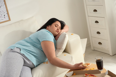 Photo of Lazy overweight woman with pizza on sofa at home